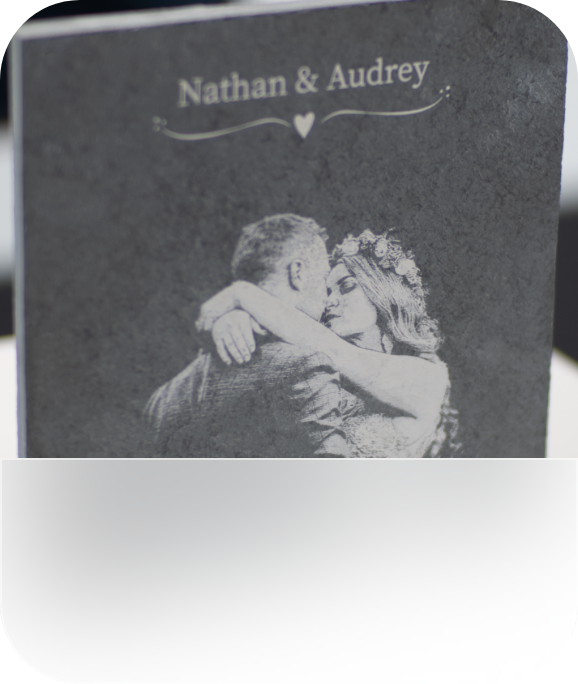 A laser-engraved natural stone tile with names and a bride and groom on it.