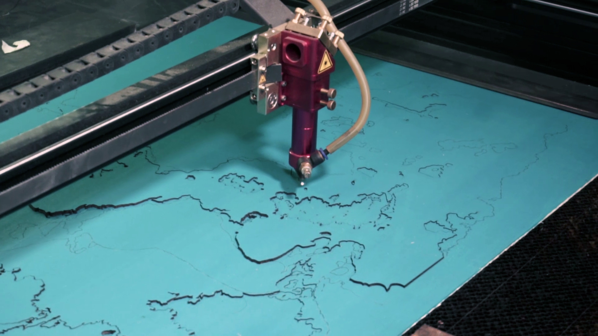 A laser machine cuts out a decorative map.