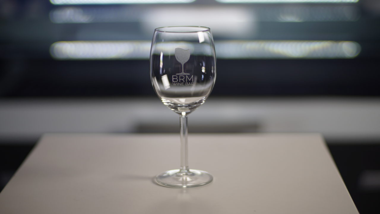 Ein lasergraviertes Glas mit einem Bar-Logo darauf.
