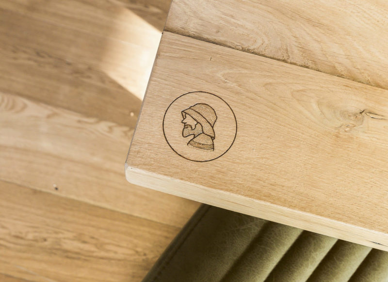 Een logo gegraveerd op een houten tafelblad in een restaurant.